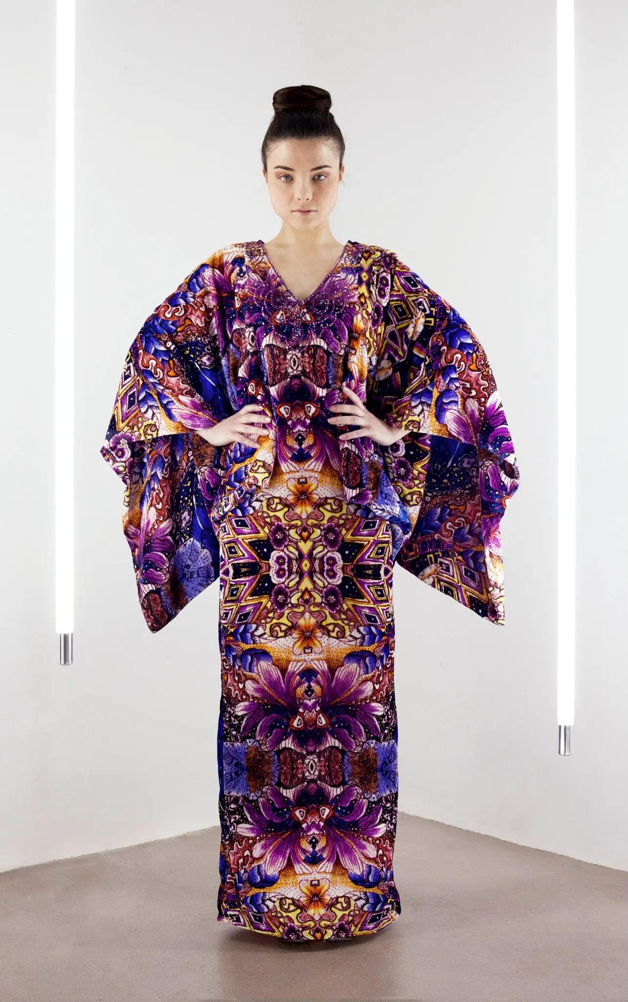 Model wearing a full-length silk velvet kaftan with a psychedelic floral print and exaggerated cape sleeves.